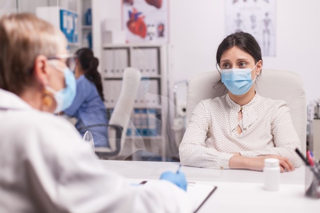 stressed-young-patient-with-face-mask-against-covid-19-during-consultation-with-senior-doctor-hospital-office-terrified-woman_482257-9855